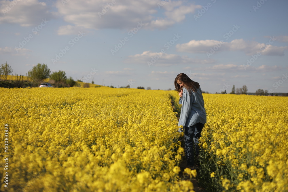 young beautiful woman in a field with yellow blooming rapeseed. girl in yellow floral field, rapeseed plantation, summer vacation concept