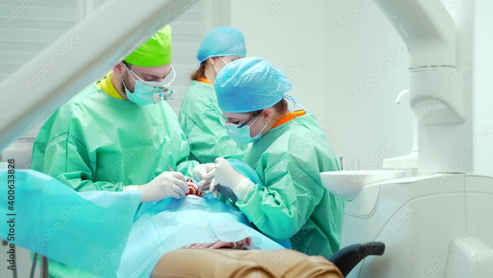 team of dental surgeons performs surgery on teeth. in a modern clinic. Young dentist. Teamwork. Tooth doctor orthodontist surgeon doing medical operation on root canals. Stomatology office team of dental surgeons performs surgery on teeth. in a modern clinic. Young dentist. Teamwork. Tooth doctor orthodontist surgeon doing medical operation on root canals. Stomatology office