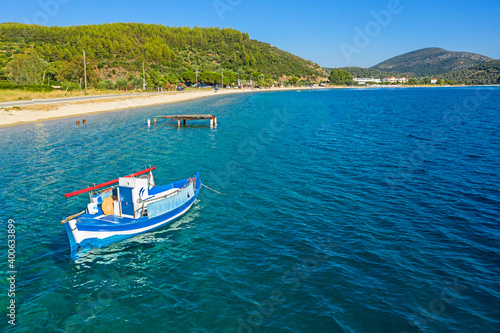Panorama of Mediterranean sea coastline, Greece, Halkidiki, Sithonia. Top view of sail boat in blue water, white sand beach, pine forest background
