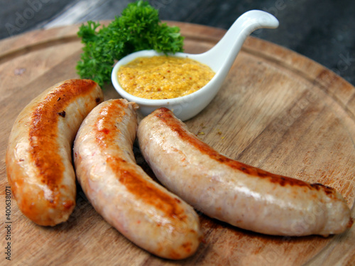 Grilled pork sausages with mustard on a wooden plate