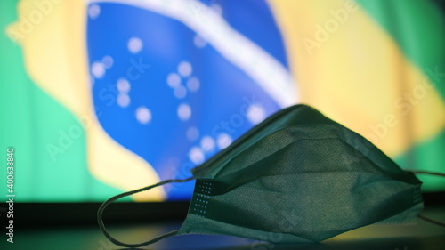 Face mask against blurred flag of Brazil. Brazilian COVID-19 outbreak concept
