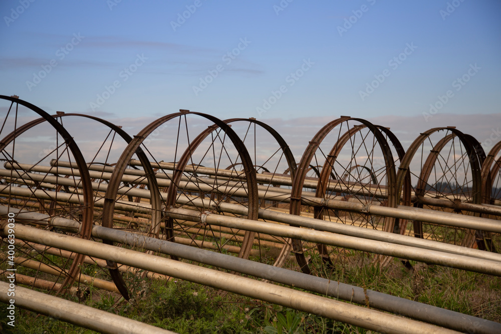 An isolated view of an unassembled wheel line irrigation system under a blue sky