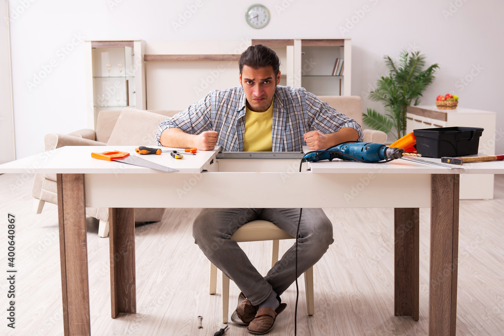 Young male carpenter repairing furniture at home Young male carpenter repairing furniture at home