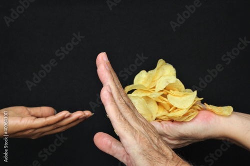 Miser concept, blur woman hand asking potato chips from hands of miser man. stock photo photo