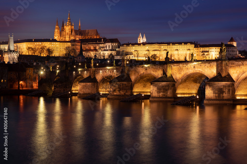 . prague castle and charles bridge and st. vita church lights from street lights are reflected on the surface of the vltava river in the center of prague at night in the czech republic © svetjekolem