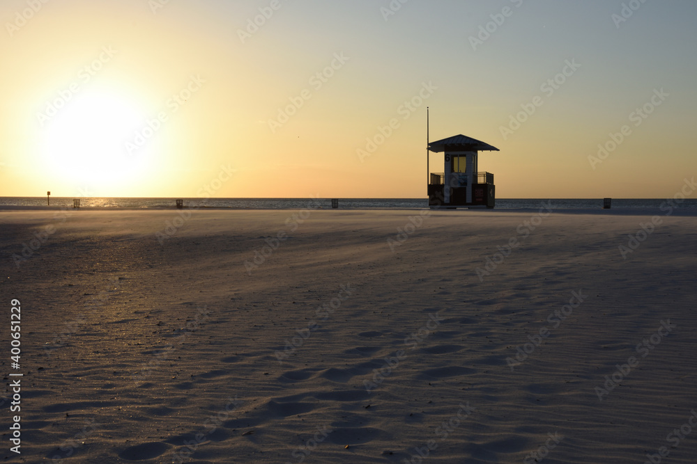 Lifeguard stand on the beach at sunset with wind blowing the sand. Copy space.
