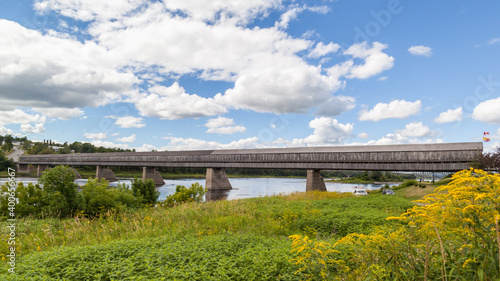 NEW  BRUNSWICK, CANADA - August 6, 2017: Side view of Hartland covered  bridge in New Brunswick. This 390-m (1,282-ft.) bridge opened on 1901, the longest wooden covered bridge in the world.  photo