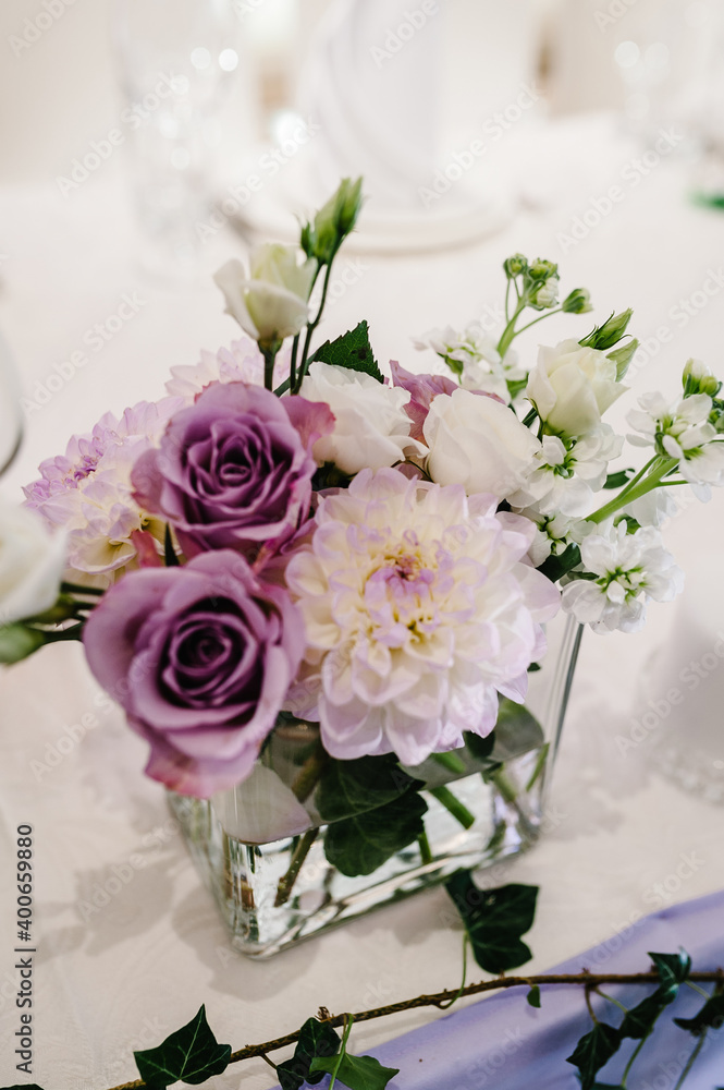 Composition of violet, white flowers and greenery on table. Home decor. Wedding decoration. Composition of violet, white flowers and greenery on table. Home decor. Wedding decoration.