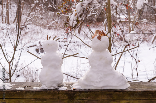 Two miniature snowmen, depicting a boy and girl on a wooden railing in Frick Park on a winter day in Pittsburgh, Pennsylvania, USA photo