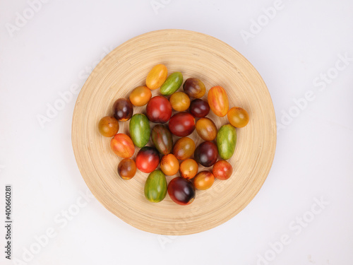 Fototapeta Naklejka Na Ścianę i Meble -  Red orange yellow green tomato mix variety on wooden plate over white background