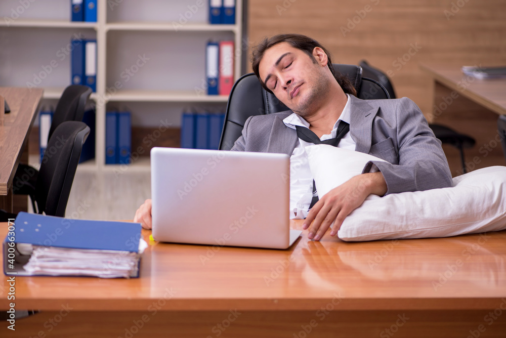 Fototapeta premium Young male employee sleeping at workplace