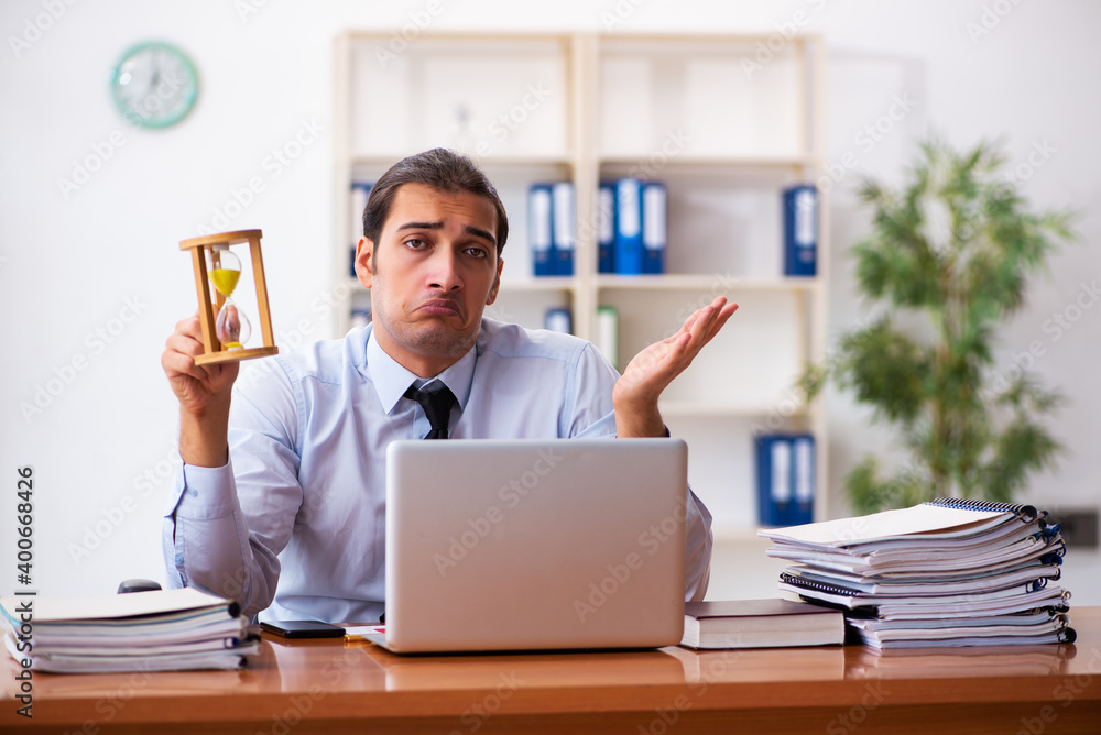Young male employee in time management concept Young male employee in time management concept