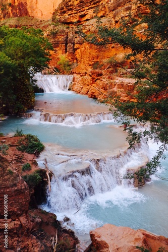 Havasupai falls with multiple blue waterfalls in red canyon and trees