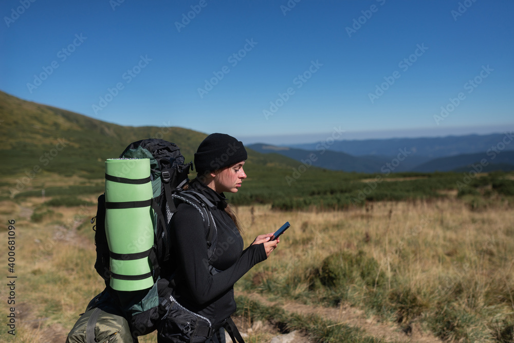 woman hiker stands on the top of the mountain, holds the phone in her hands and types a message. Baner.