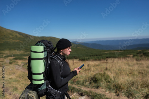 woman hiker stands on the top of the mountain, holds the phone in her hands and types a message. Baner.