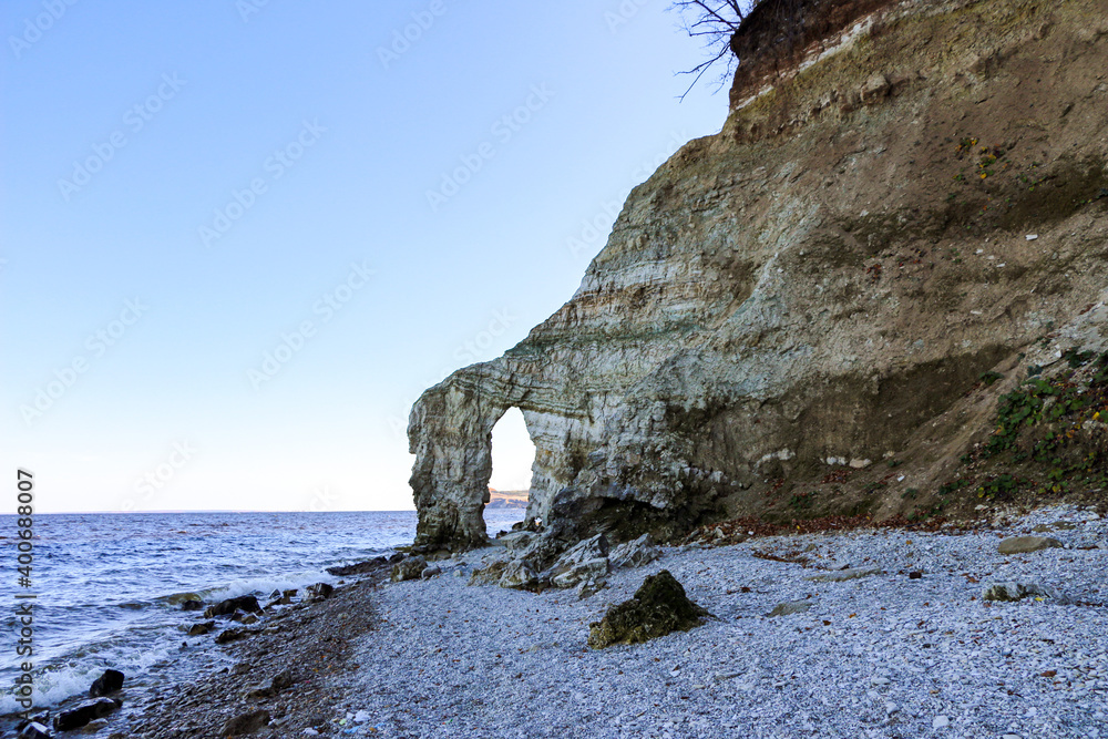 rocky stone arch from various natural rocks, on river bank. layered ...