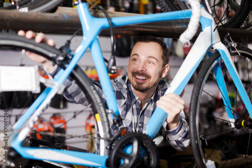 Handsome man considers bicycle frame in store when choosing bike