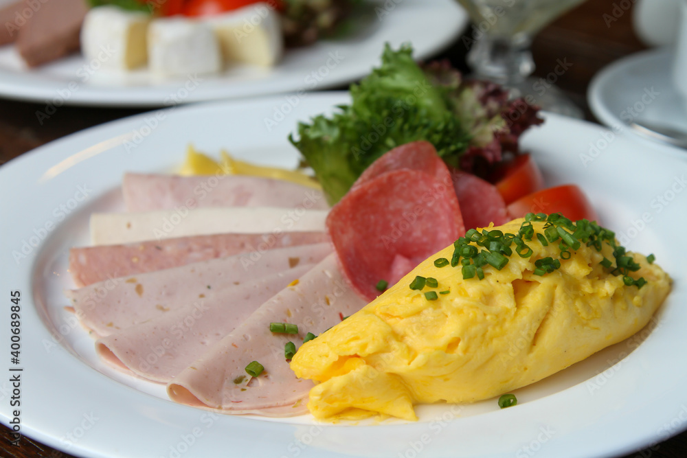 German breakfast with scrambled egg, cold cuts, cheese, lettuce, tomato and cucumber German breakfast with scrambled egg, cold cuts, cheese, lettuce, tomato and cucumber