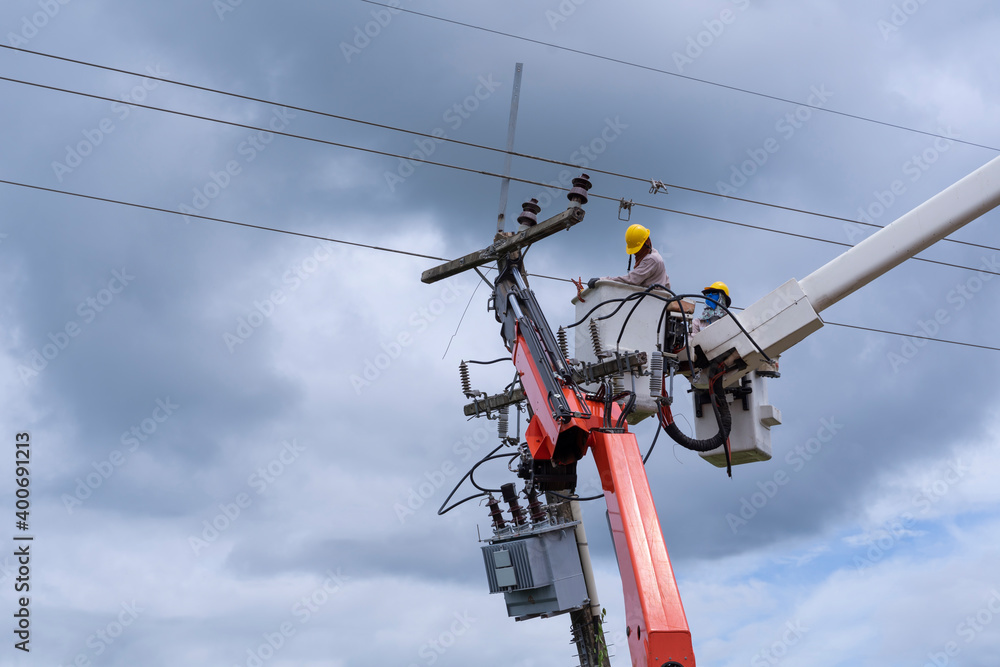electrician works on bucket car to maintain high voltage transmission lines.