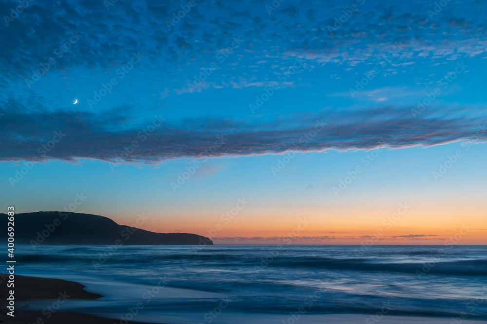 Obraz premium High cloud, partial moon and a pretty blue dawn at the beach