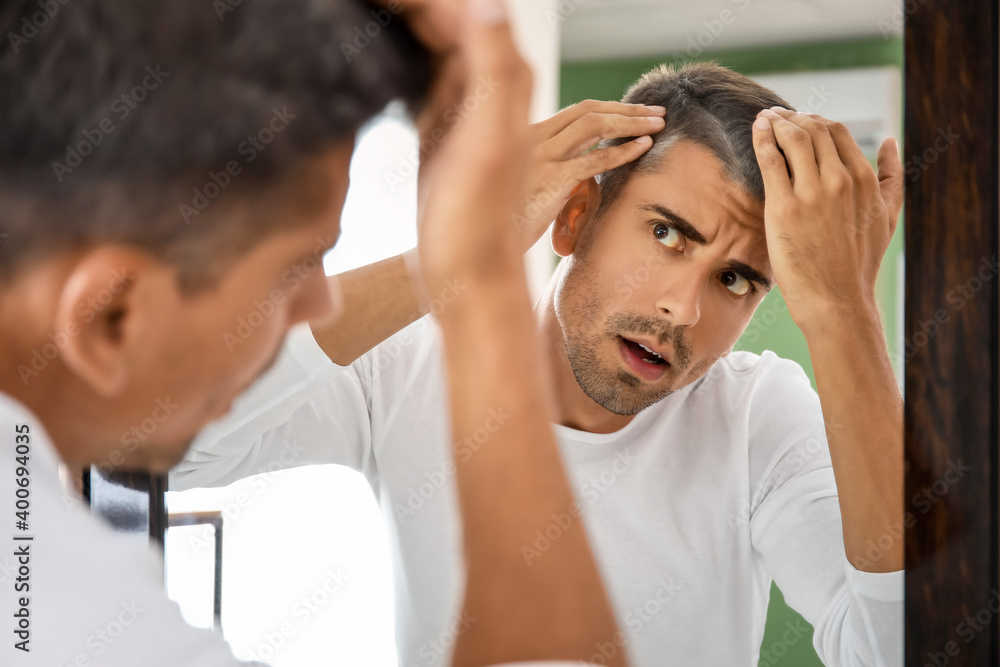 Stressed man with graying hair looking in mirror Stressed man with graying hair looking in mirror