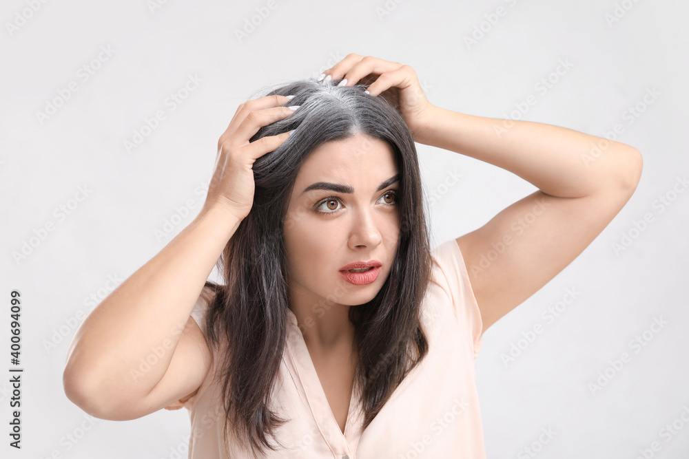 Stressed woman with graying hair on light background Stressed woman with graying hair on light background