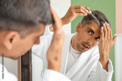 Man with graying hair using serum at home