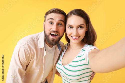 Young couple taking selfie on color background