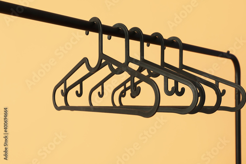 Rack with clothes hangers on color background