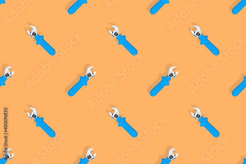 Wrench on an orange background. Seamless background from adjustable metal wrench. Seamless patterns.