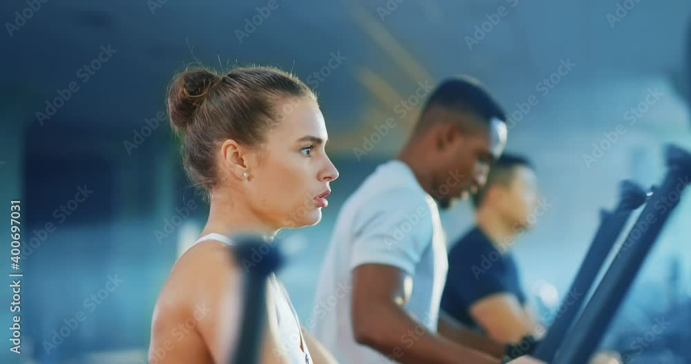 Healthy active multi-race young athletes male and female training together intense workout on cross trainers in contemporary gym. Bodybuilding. Fitness. Healthy active multi-race young athletes male and female training together intense workout on cross trainers in contemporary gym. Bodybuilding. Fitness.