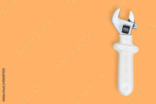 Wrench on an orange background. Seamless background from adjustable metal wrench.