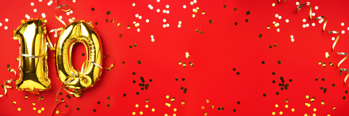 Gold foil balloon number, digit ten. Birthday greeting card with inscription 10. Anniversary celebration event. Banner. Golden numeral, red background. Numerical digit, light bokeh, glitter