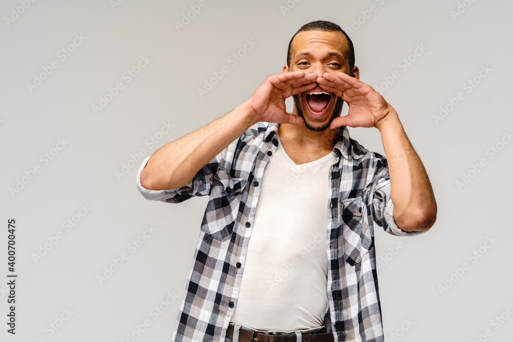 young african american man shouting against a grey background young african american man shouting against a grey background
