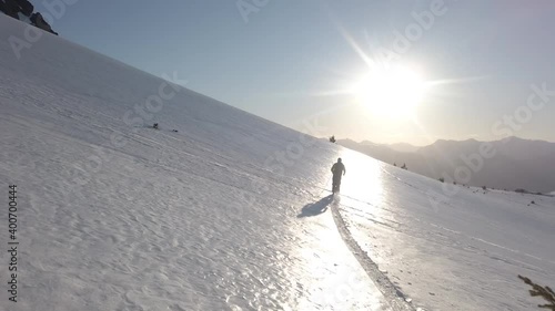 Dolly in following a man skiing alone across snow covered Piltriquitron Hill at sunset, El Bolsón, Patagonia Argentina. photo