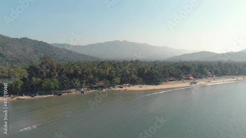 Coastal exotic shoreline and tourist beach resort in Palolem Beach, in Goa, India - Aerial wide slide shot photo