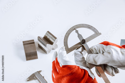 The worker measures the angle on the metal product with a protractor. photo