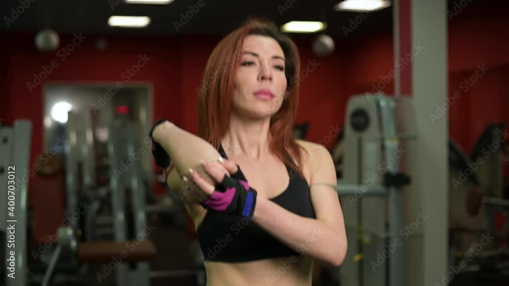 Young woman warming up and doing stretching while walking on a treadmill in a gym Young woman warming up and doing stretching while walking on a treadmill in a gym