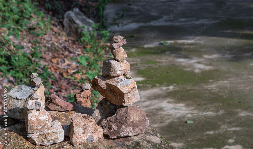 Balanced stone tower on walkway up the mountain with green plants in the background. Selective focus. Balanced stone tower on walkway up the mountain with green plants in the background. Selective focus.