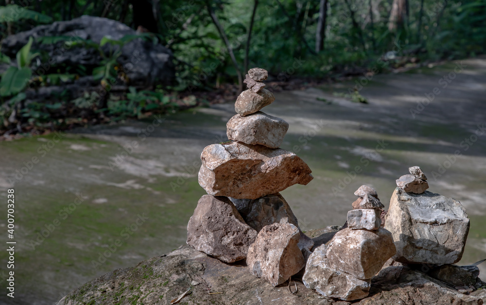 Balanced stone tower on walkway up the mountain with green plants in the background. Selective focus. Balanced stone tower on walkway up the mountain with green plants in the background. Selective focus.