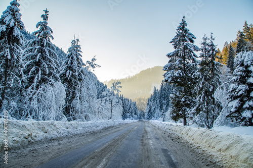 a road that runs through a snowy forest and mountains. Winter season.