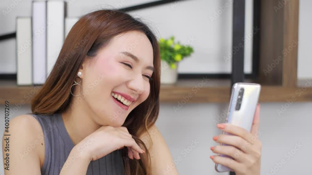 portrait of Asian woman making a video call using smart phone with friends, Happy Girl talking online sitting with phone. portrait of Asian woman making a video call using smart phone with friends, Happy Girl talking online sitting with phone.