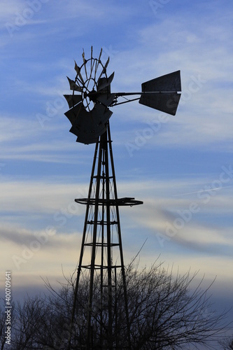 windmill at sunset with blue sky and white clouds north of Hutchinson Kansas USA.