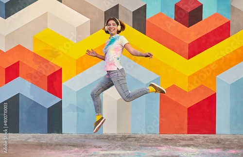 Excited young woman jumping against geometric wall