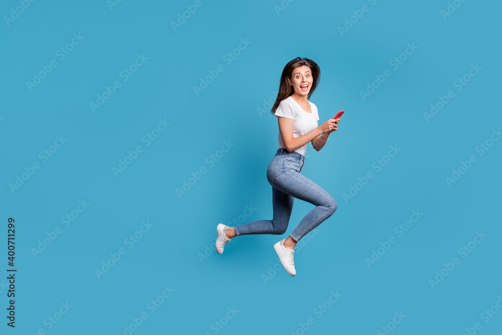 Full body profile side photo of shocked student run jump copyspace wear casual outfit hold phone isolated on blue color background