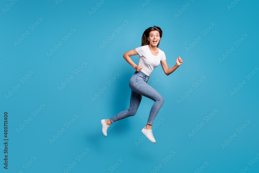 Full body profile side photo of nice funky woman amazed sale run jump empty space wear jeans isolated on blue color background
