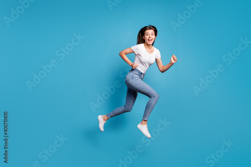 Full body profile side photo of nice funky woman amazed sale run jump empty space wear jeans isolated on blue color background