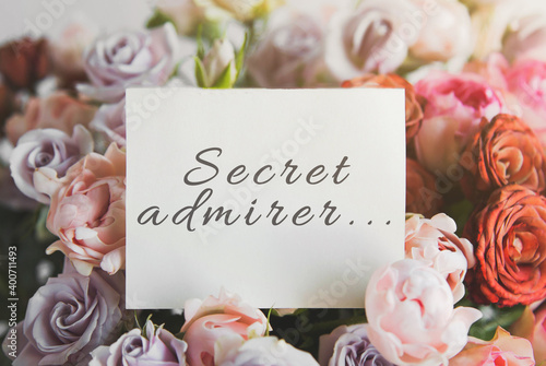 white card for a bouquet with the inscription secret admirer in a bright beautiful bouquet of flowers roses
