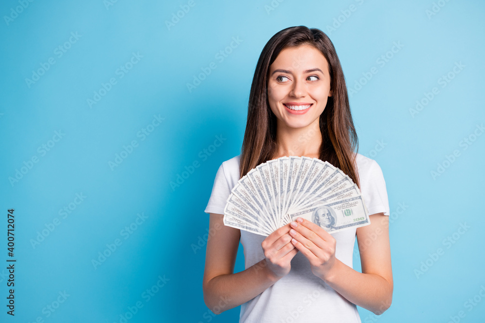 Photo of young cheerful smiling good mood lovely rich girl holding dollars money isolated on blue color background Photo of young cheerful smiling good mood lovely rich girl holding dollars money isolated on blue color background