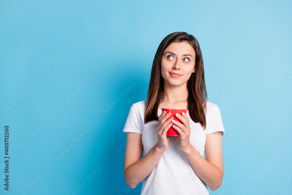 Photo of young happy dreamy lovely pretty cute girl look copyspace drinking tea from red mug isolated on blue color background Photo of young happy dreamy lovely pretty cute girl look copyspace drinking tea from red mug isolated on blue color background